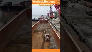 A bulldozer pushes stones into piles in a ships hull for a crane to load onto trucks [upl. by Aicitel]